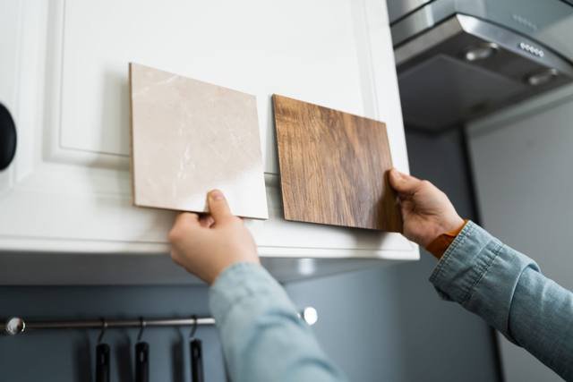 Two laminate door samples, a light stone-look and a walnut timber-look, held against a white cabinet