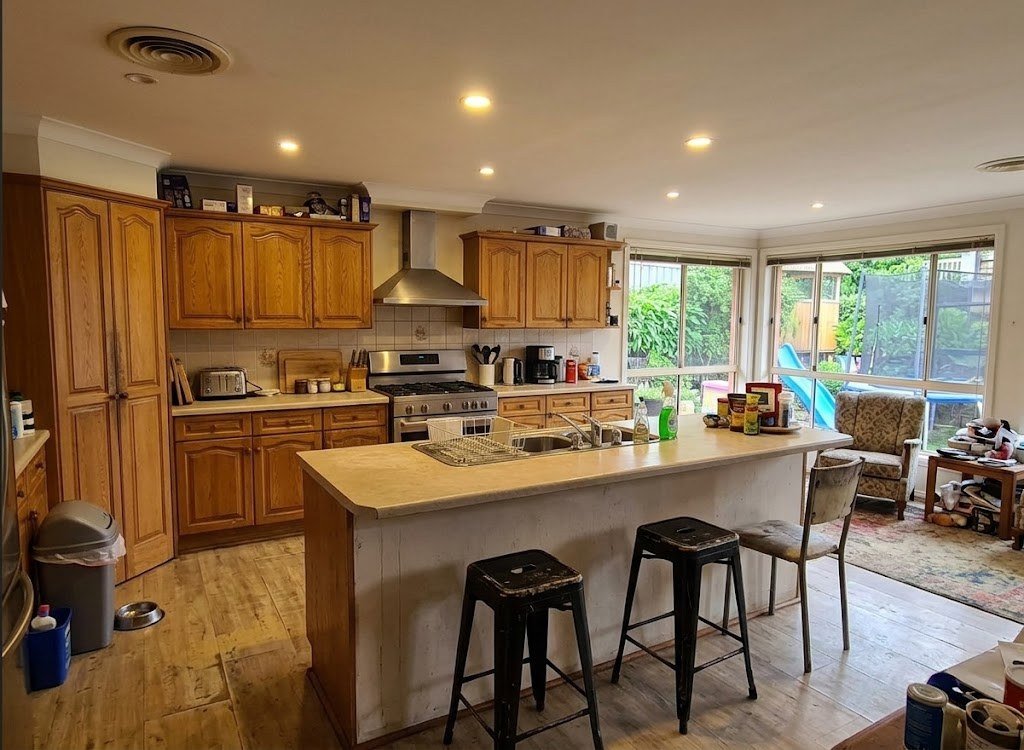 A kitchen with white arched-door cabinets and a grey benchtop, before its facelift