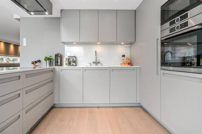 A kitchen with light grey custom doors fitted to flat-pack cabinets