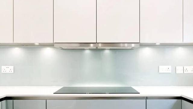 A pale glass splashback above a cooktop